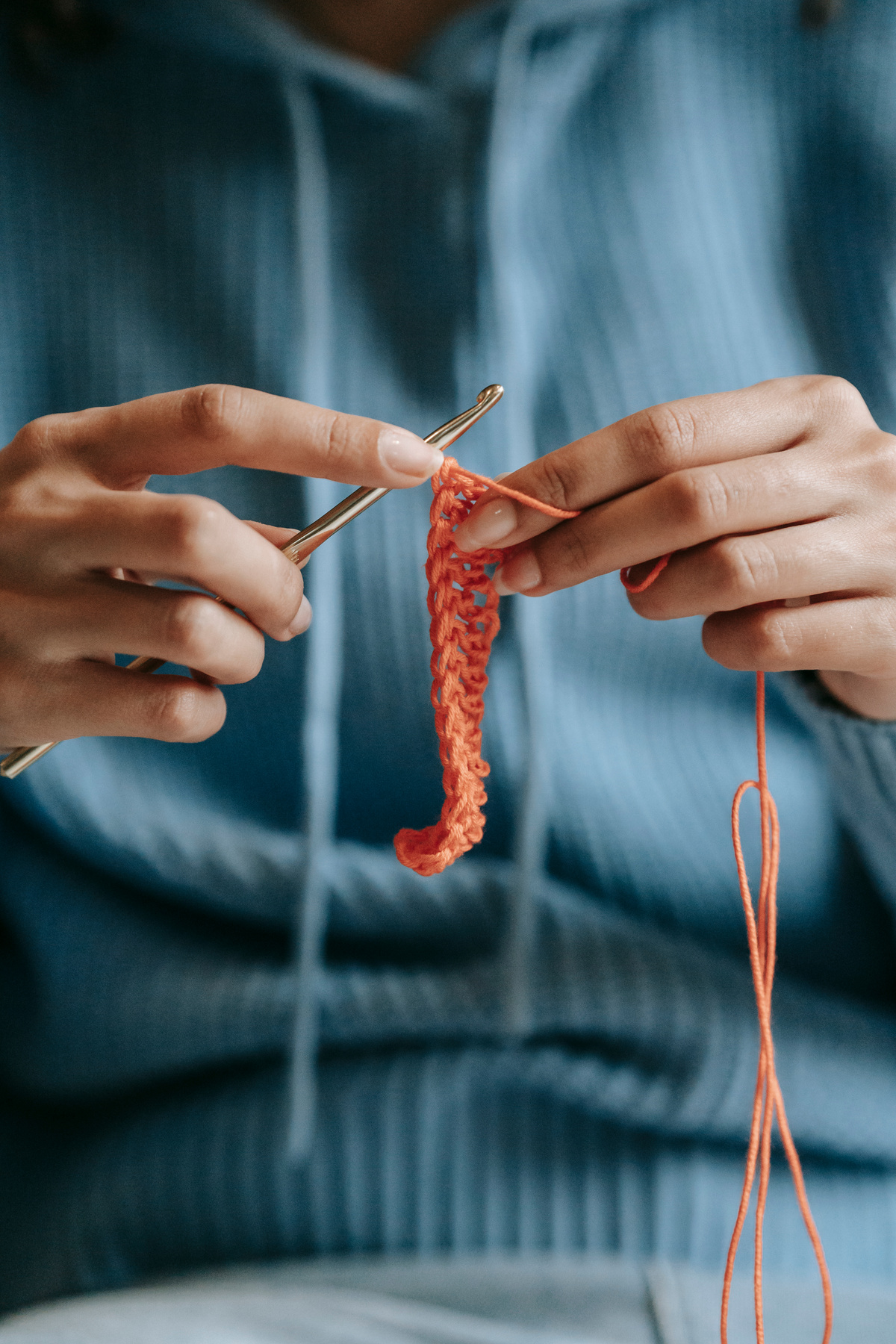 Woman knitting with orange threads and crochet